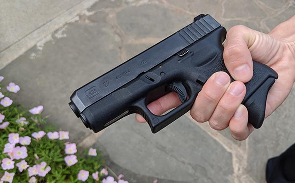 glock 27 in small female hands, extended grip on magazine